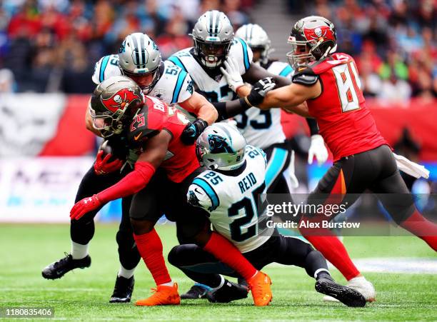 Peyton Barber of Tampa Bay Buccaneers is tackled by Luke Kuechly and Eric Reid of Carolina Panthers during the NFL match between the Carolina...