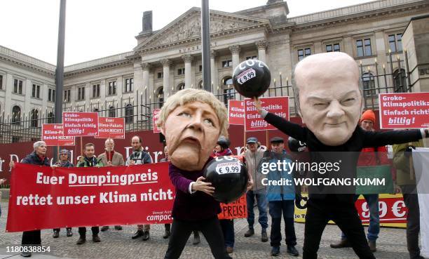 Activists wear masks of German Chancellor Angela Merkel and German Finance Minister and Vice-Chancellor Olaf Scholz as they protest against the...