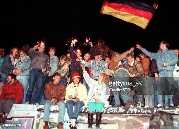 This photo taken on November 11, 1989 in Berlin shows young East Berliners celebrating atop the Berlin Wall. - The fall of the Berlin Wall in 1989,...