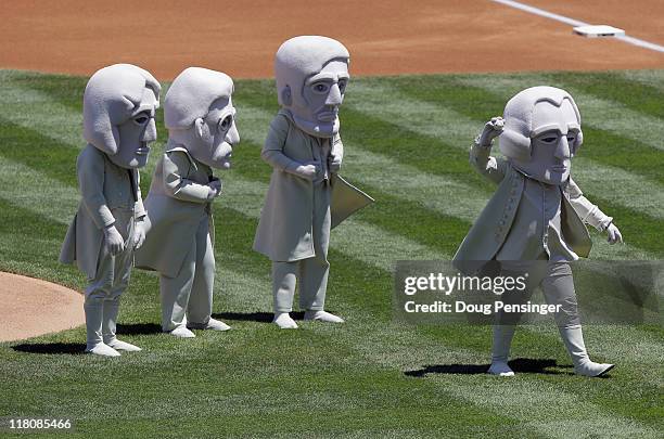 Representing the US Presidents sculpted on Mount Rushmore, George Washington throws out the ceremonial first pitch as Thomas Jefferson, Theodore...