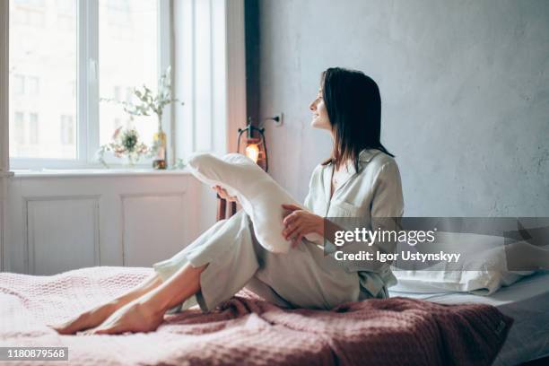 young woman looking out of window - roupa de dormir - fotografias e filmes do acervo