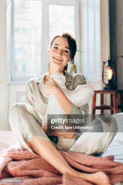 young happy woman embracing pillow - silk pillow stock-fotos und bilder