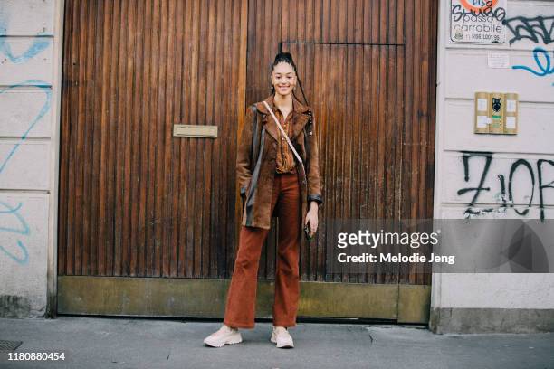 Model Indira Scott wears brown suede jacket, brown print shirt, brown corduroy pants, and white shoes after the Byblos show on Day 1 Milan Fashion...