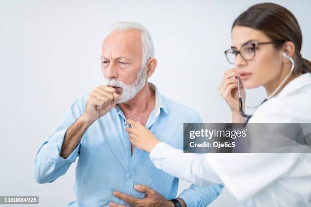 senior man having his lungs examined with stethoscope. - old cough stock pictures, royalty-free photos & images