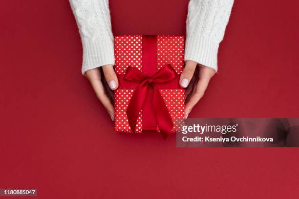 woman hands holding present box with red bow on pastel pink background with multicolored confetti. flat lay style. - dar fotografías e imágenes de stock