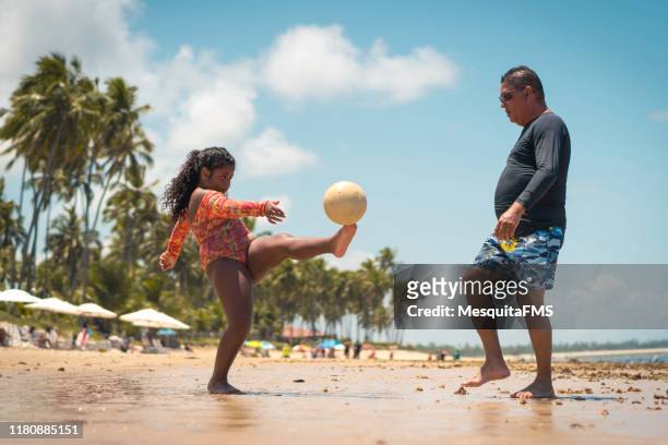 father playing soccer with his daughter on the beach - beach football stock pictures, royalty-free photos & images
