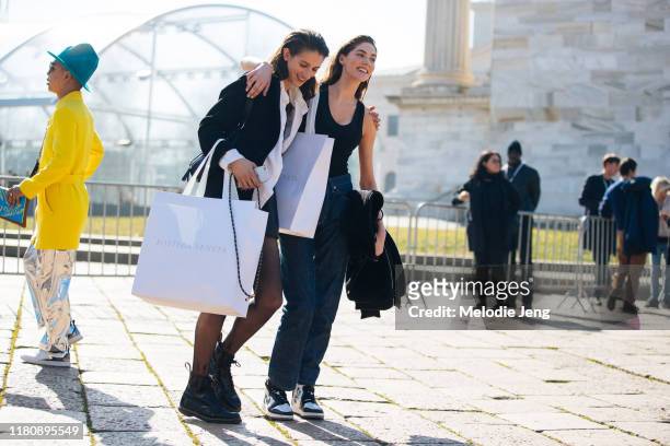 Models Rachel Marx and Zelda Heloise Smyth walk and carry loarge white Bottega Veneta shopping bags after the Bottega Veneta show on Day 3 Milan...