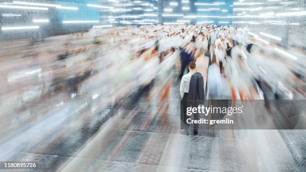 businessman standing in the fast moving crowds of commuters - crowded airport stock pictures, royalty-free photos & images