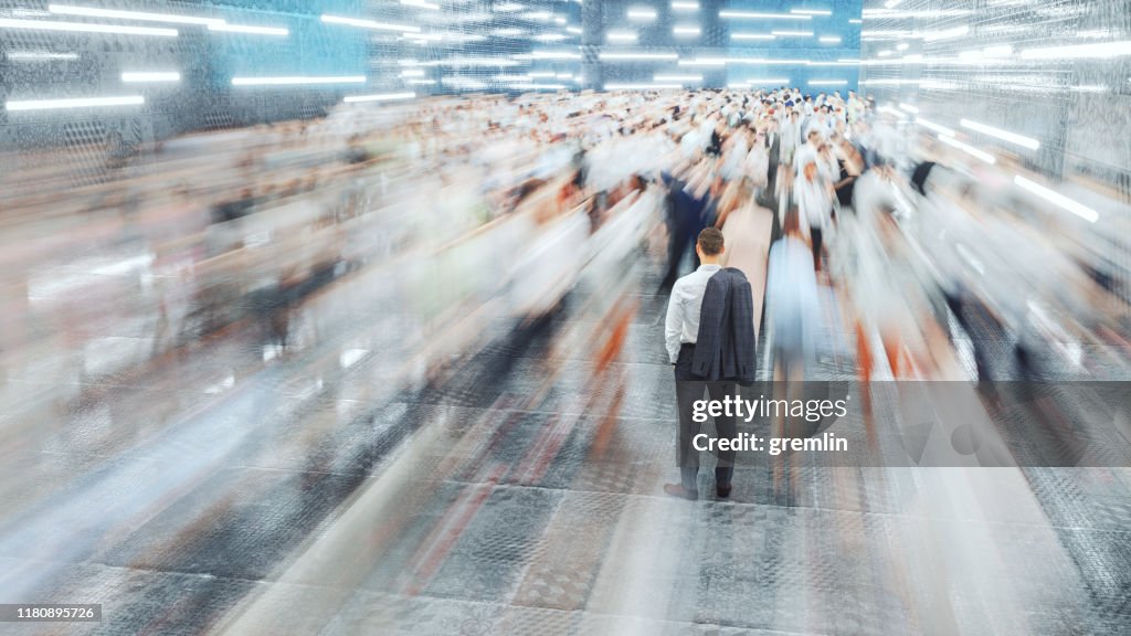 Homem de negócios que está nas multidões moventes rápidas dos passageiros