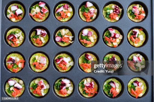 octopus grill recipe. put the cut takoyaki material into the hole in the iron plate.angle shot from above. - takoyaki stock pictures, royalty-free photos & images