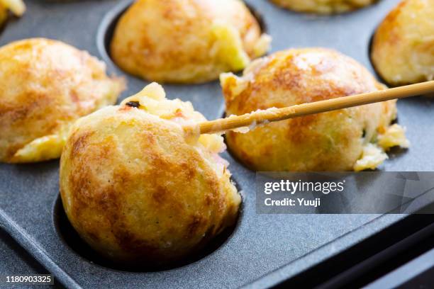 octopus grill recipe. turn the baked takoyaki over with a skewer. - takoyaki stock pictures, royalty-free photos & images