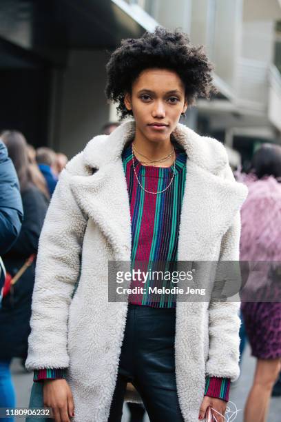 Model Ashanti Hildreth wears a white shearling jacket, colorful striped pants, and black pants after Dolce & Gabbana on Day 5 Milan Fashion Week...