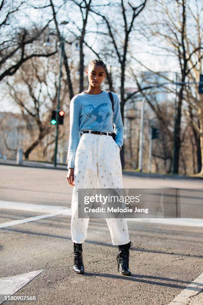 Model Blesnya Minher wears a blue Alberta Ferretti "help me" earth environmentalist sweater, white studded pants, and black booties after the...