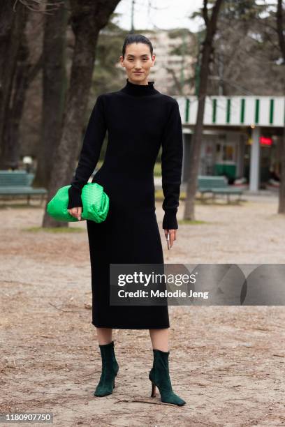 Model Lina Zhang wears a fitted black dress, green Bottega Veneta clutch, and green velvet heels after the Roberto Cavalli show on Day 4 Milan...