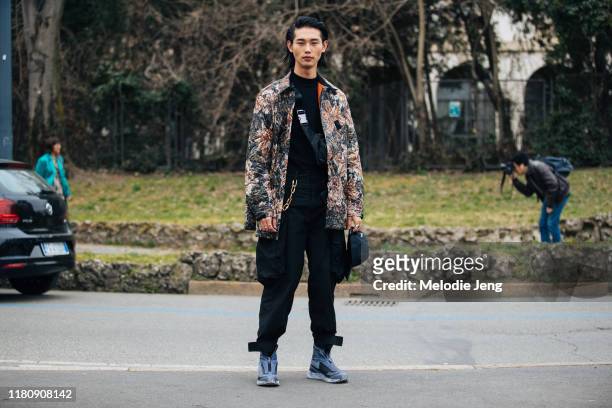 Model Taemin Park wears a floral Y-3 jacket, black cargo pants, and dark blue Boris Bidjan Saberi x Salomon zip sneakers after the Roberto Cavalli...