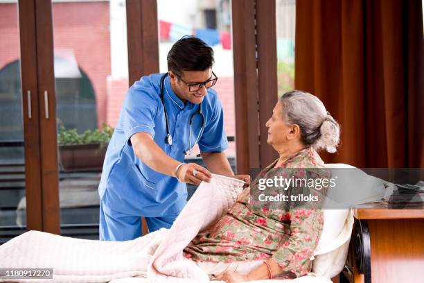 mannelijke verpleegkundige thuis verzorger helpen senior vrouw ontspannen op bed - daily life in india stockfoto's en -beelden