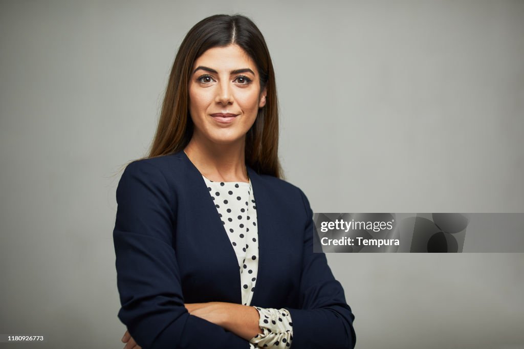 Studio waist up portrait of a beautiful businesswoman with crossed arms.