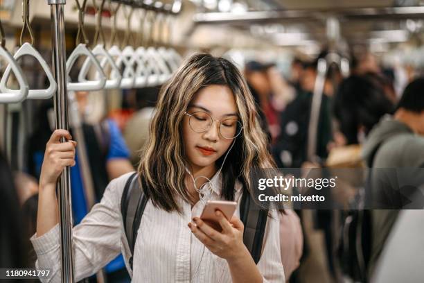mensajes de texto a su amigo en su camino a la escuela en el metro - asian teen girl fotografías e imágenes de stock