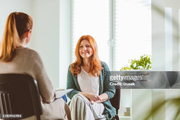 smiling woman with therapist at community center - mental health professional stock pictures, royalty-free photos & images