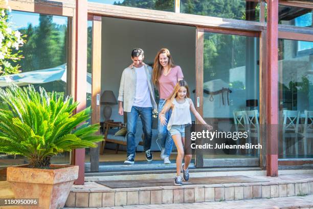 famiglia sorridente che si sposta all'aperto nel cortile dell'agriturismo - porta scorrevole foto e immagini stock