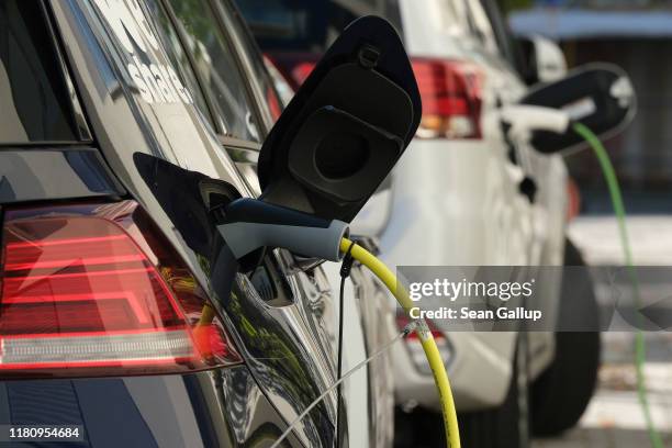An electric car and a plug-in hybrid car charge at a public charging station on October 12, 2019 in Berlin, Germany. Germany is hoping to encourage...