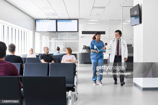 doctor and nurse walking by patients in lobby - sala de espera imagens e fotografias de stock