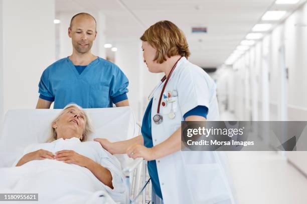 doctor consoling senior patient at hospital - hospital doctor stock pictures, royalty-free photos & images