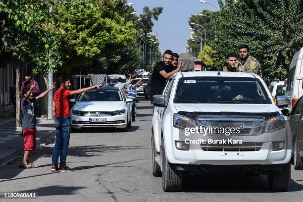 People wave as members of Turkish-backed Free Syrian Army, a militant group active in parts of northwest Syria, heading toward Syrian town of Tal...