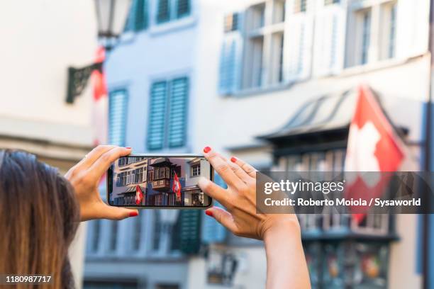 woman with smartphone photographing flags, zurich - flagge schweiz stock-fotos und bilder