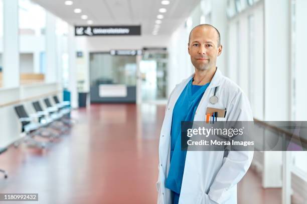 verticale de docteur restant dans le couloir d'hôpital - mains dans les poches photos et images de collection