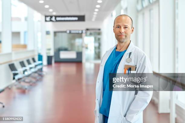 portret van een arts die in de ziekenhuis corridor staat - mannelijk stockfoto's en -beelden