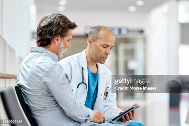 male doctor counseling mature patient at hospital - healthcare tablet image focus technique stock pictures, royalty-free photos & images