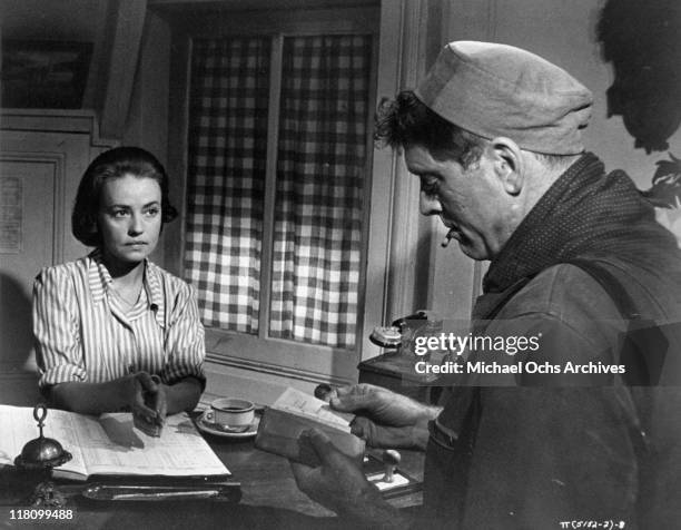 Jeanne Moreau looks on while Burt Lancaster looks at paperwork in a scene from the film 'The Train', 1964.