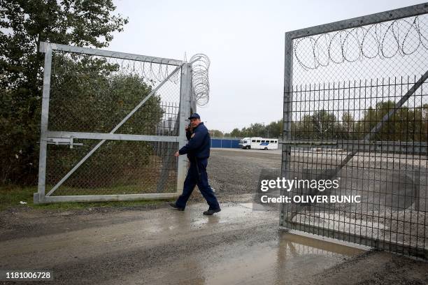 Member of hungarian police closes a razor wired fence at a migrant transit centre near Roszke, at the border crossing with Serbia on October 29,...