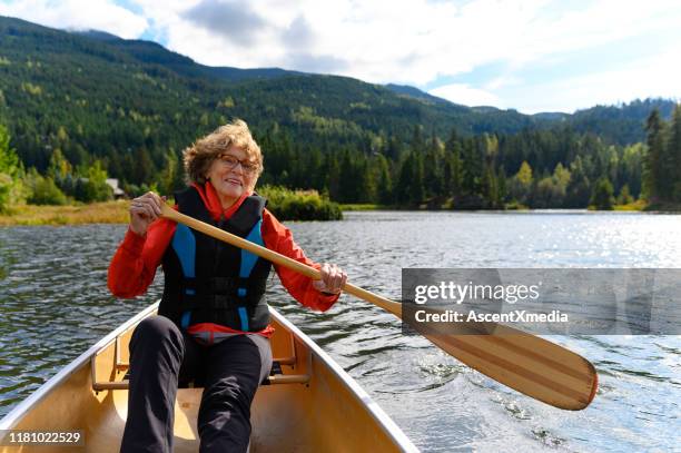 actieve senior vrouw kanoën op vakantie - kanoën stockfoto's en -beelden