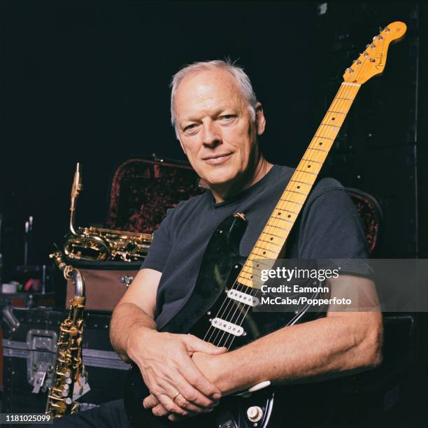 English singer, guitarist and musician David Gilmour of Pink Floyd holds a black Fender Stratocaster guitar, nicknamed The Black Strat, during a...