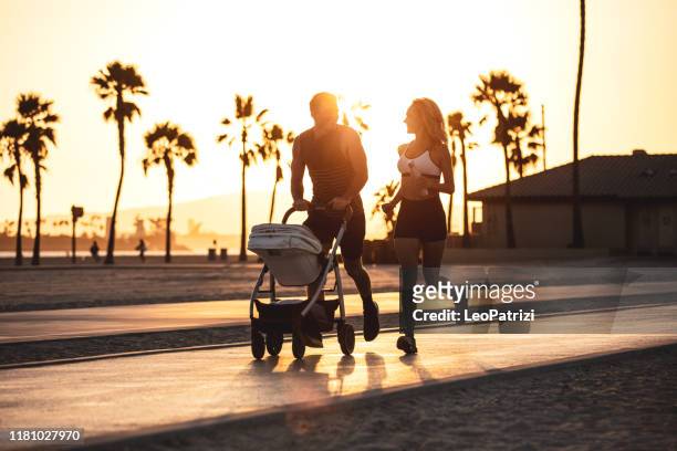 geweldige moderne en jonge familie die op het strand bij zonsondergang - long beach californië stockfoto's en -beelden