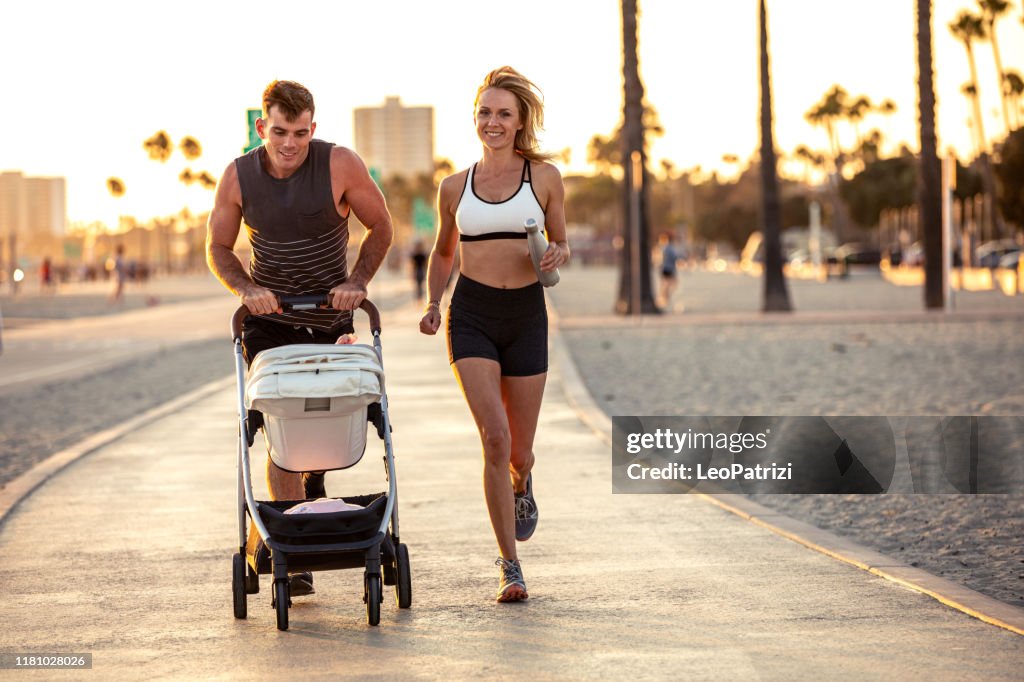 Amazing modern and young family running on the beach at sunset