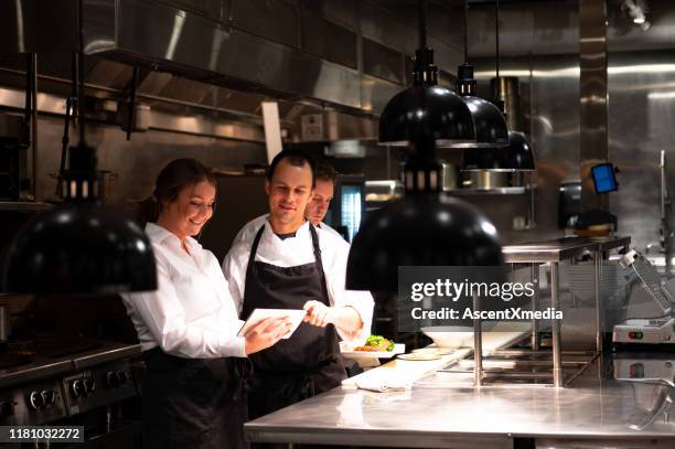 hospitality team discussing bookings on a tablet - commercial kitchen stock pictures, royalty-free photos & images