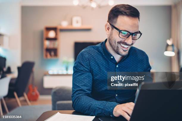 young man working at home in the evening - escritório pequeno imagens e fotografias de stock