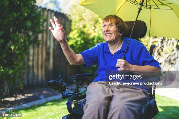 femme heureuse d'adulte aîné avec l'incapacité physique de la sclérose en plaques à l'extérieur agitant et retenant le parapluie dans la cour avant dans le colorado occidental - sclérose en plaques photos et images de collection