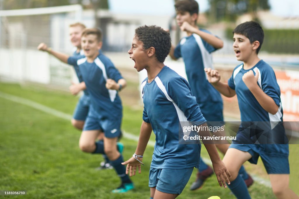 Team van zelfverzekerde jonge mannelijke voetballers die op het veld rennen