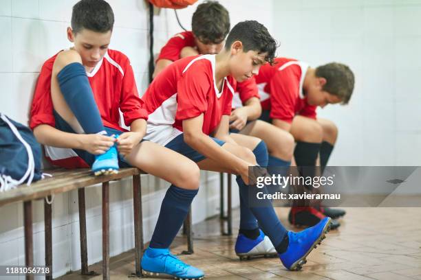 年輕的西班牙男足球員在練習前穿衣 - young boys changing in locker room 個照片及圖片檔