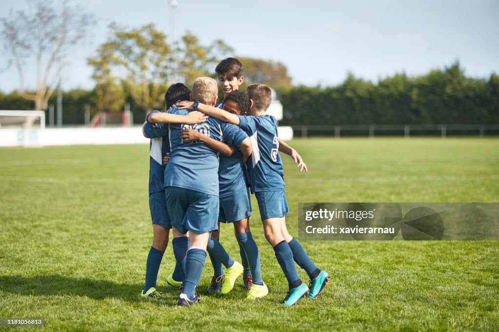 Young Male Footballers in Huddled Embrace on Field