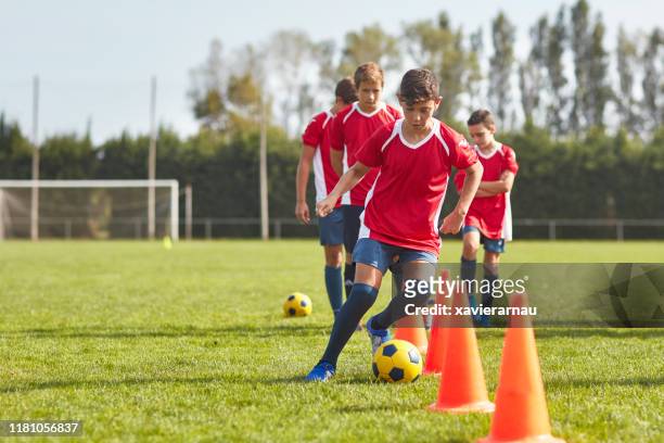 jonge spaanse voetballers dribbelen rond kegels in boor - sportoefening stockfoto's en -beelden