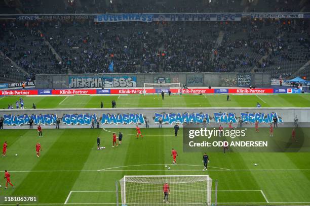 General view shows the teams warming up on either side of a mock-up of the former Berlin Wall bearing the inscrition "Together gainst Walls, together...