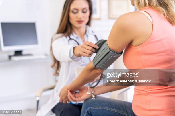 female doctor measures the blood pressure of a patient - altitude sickness stock pictures, royalty-free photos & images