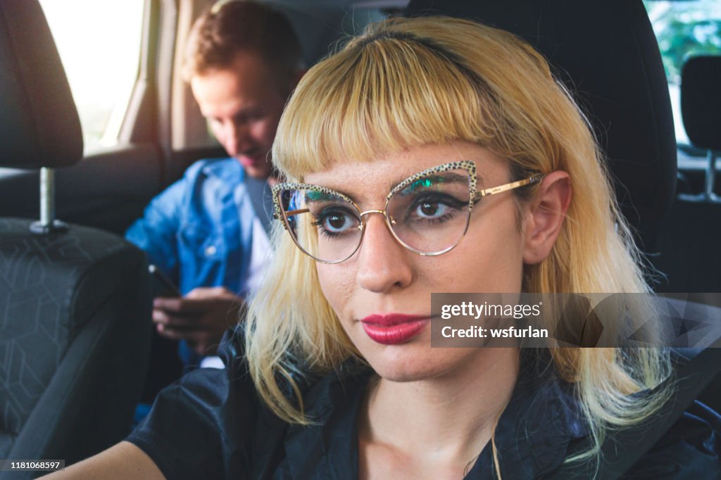 Young woman driving a car with a young man as a passenger.