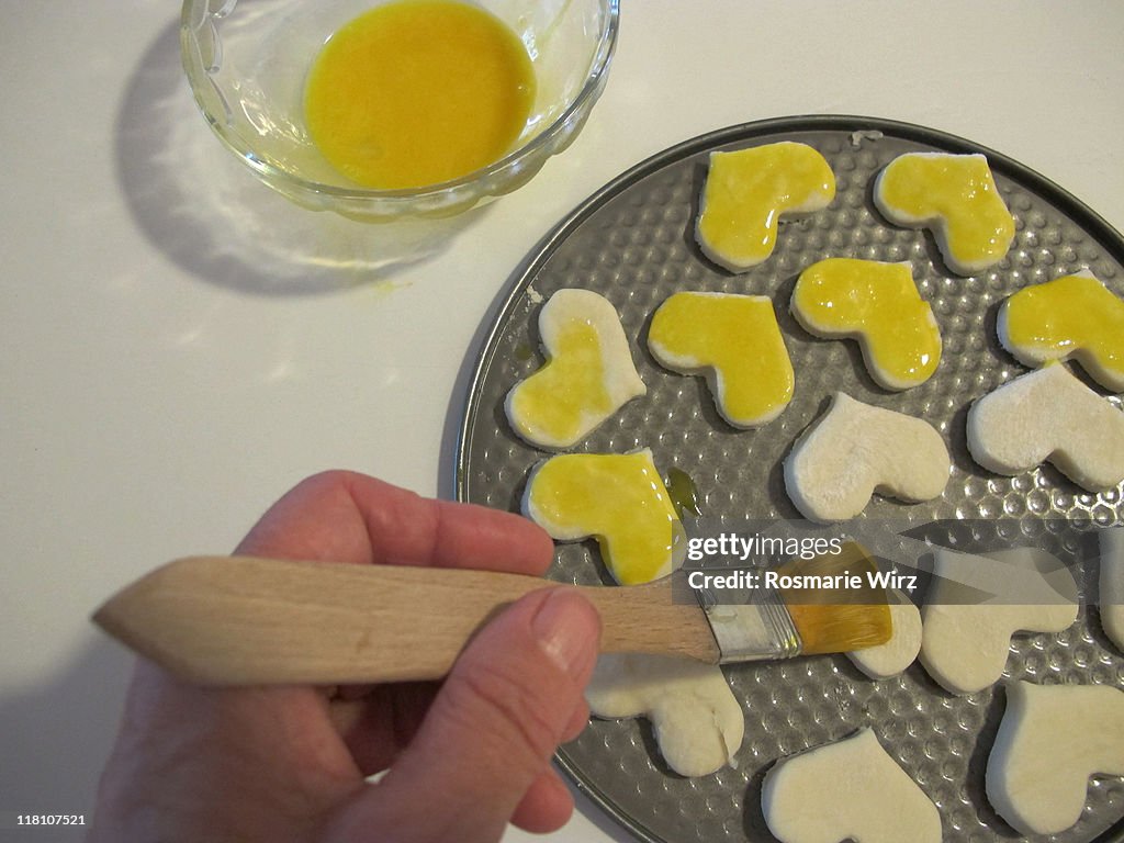 Painting pastry hearts with egg yolk