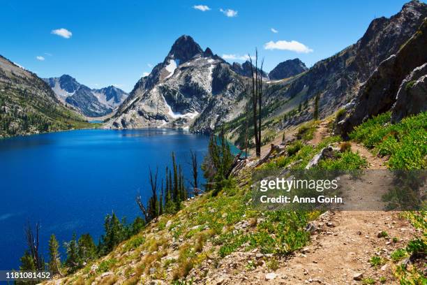 hiking trail leads along north rim of idaho's famous sawtooth lake in the sawtooth mountains outside stanley, summer afternoon - sawtooth national recreation area stock pictures, royalty-free photos & images